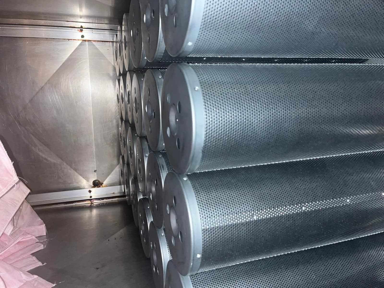 Close-up of newly installed perforated carbon filter cylinders in a filter cabinet.