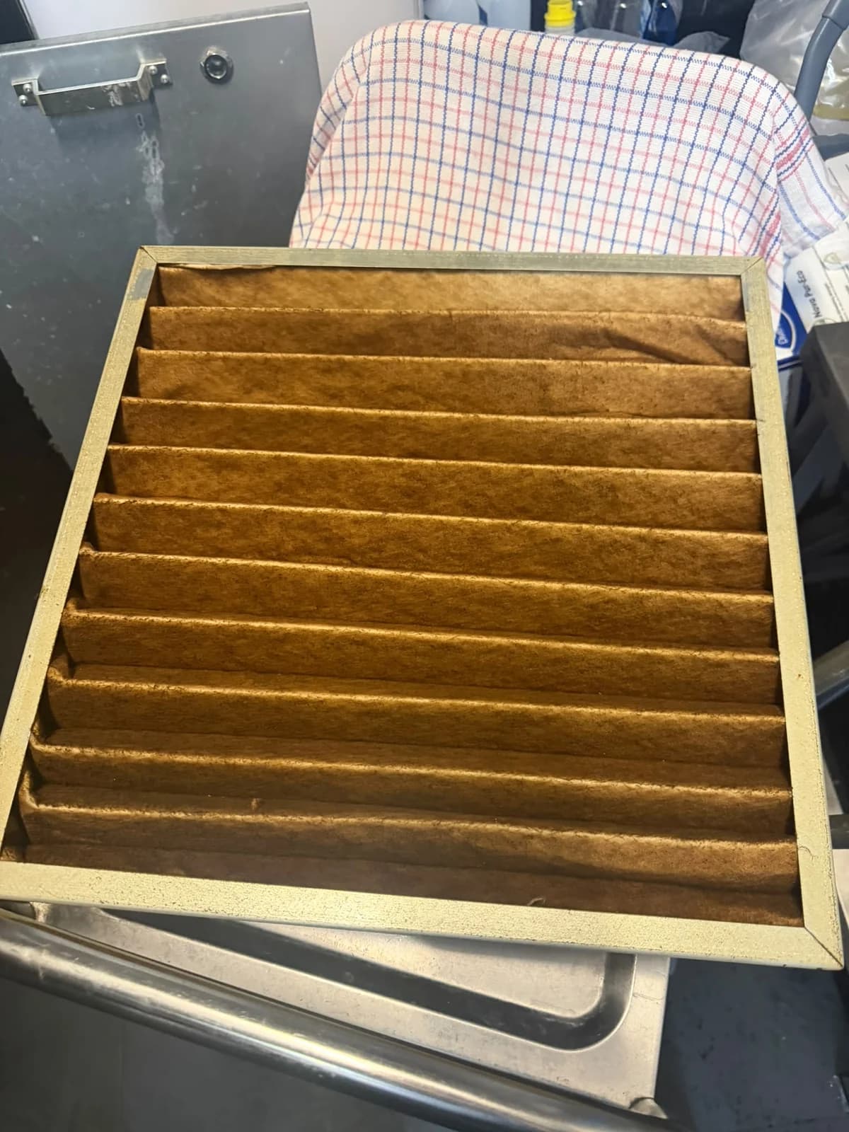 Verzadigd voorfilter paneel gedemonteerd ter inspectie vóór vervanging.