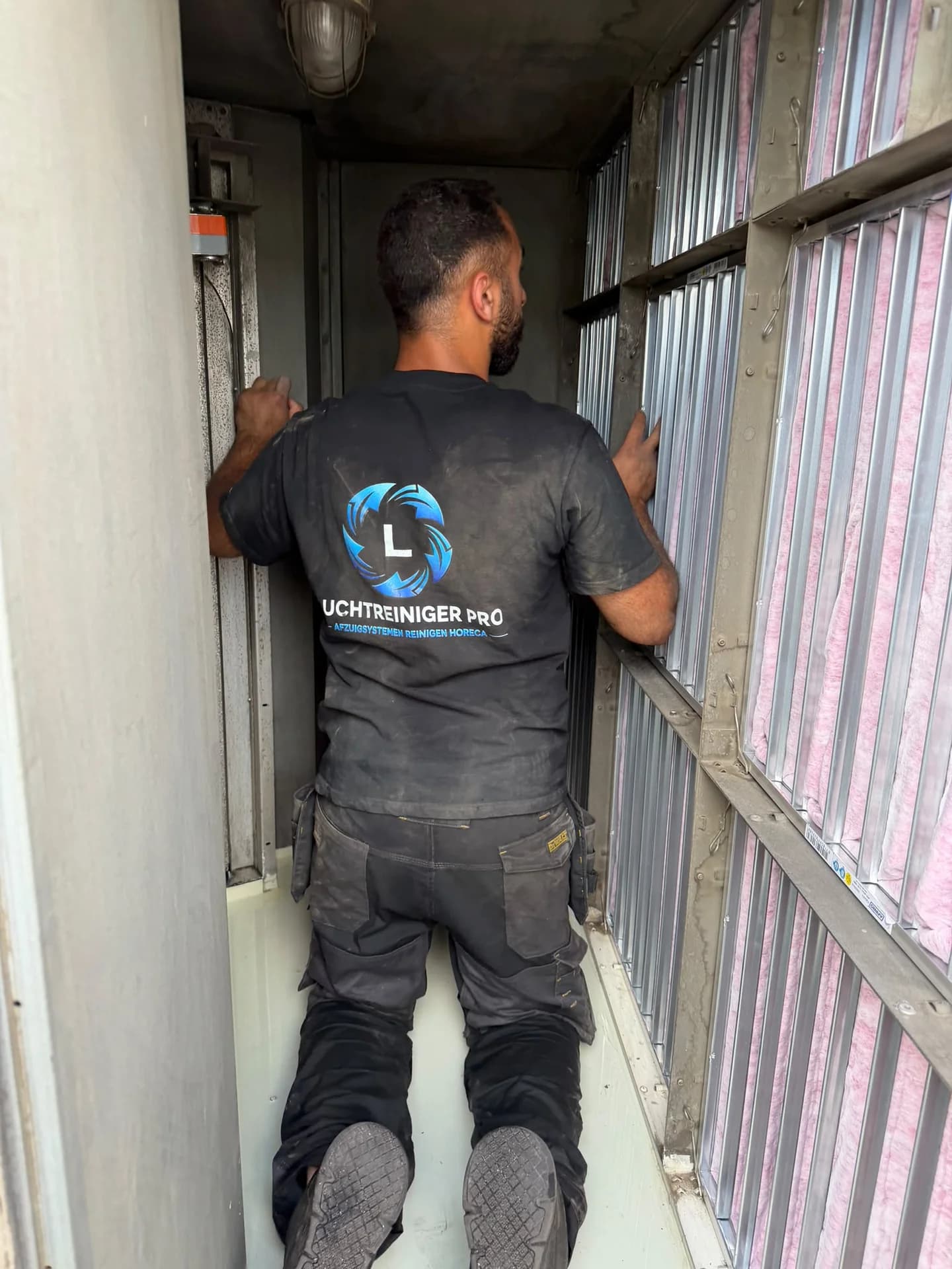Luchtreiniger Pro monteur inspecteert en vervangt zakkenfilters in een luchtbehandelingsgang.