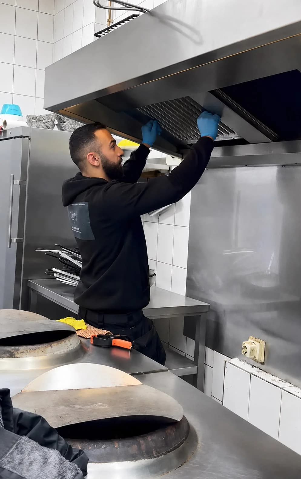Technician installing professional metal baffle filters into a commercial kitchen exhaust hood.