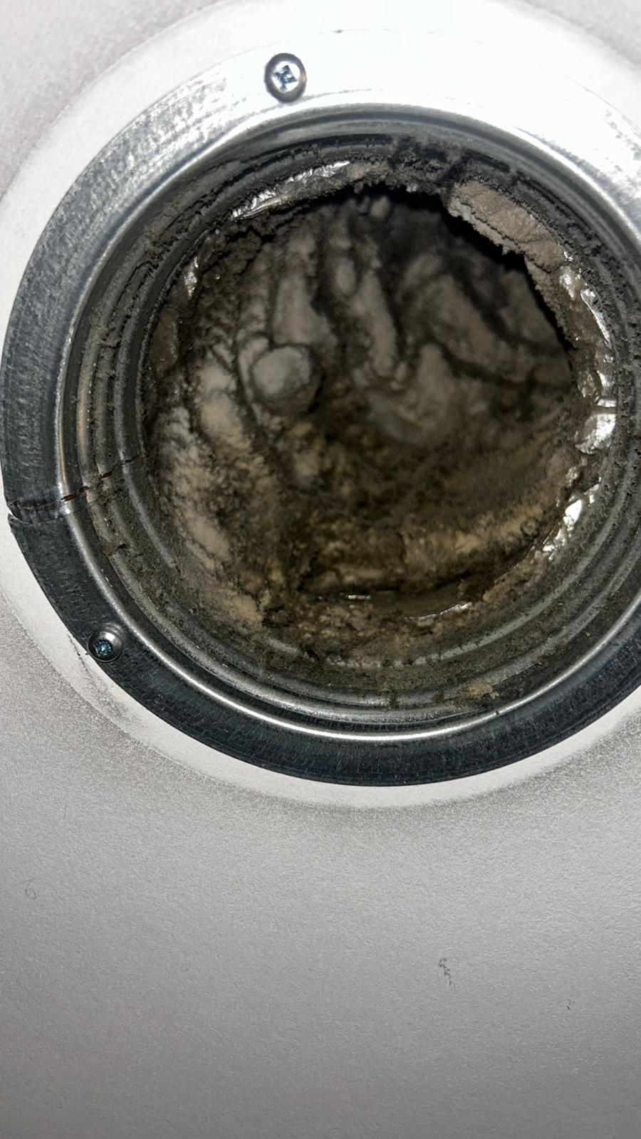 Binnenkant van een ronde ventilatieopening met zware stofafzetting