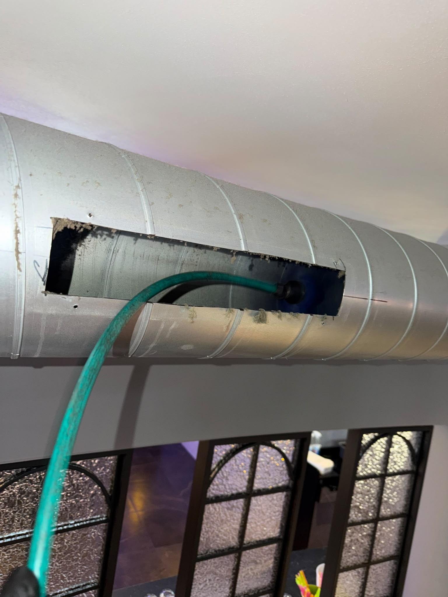 Cleaning hose through an inspection opening in a spiral metal duct