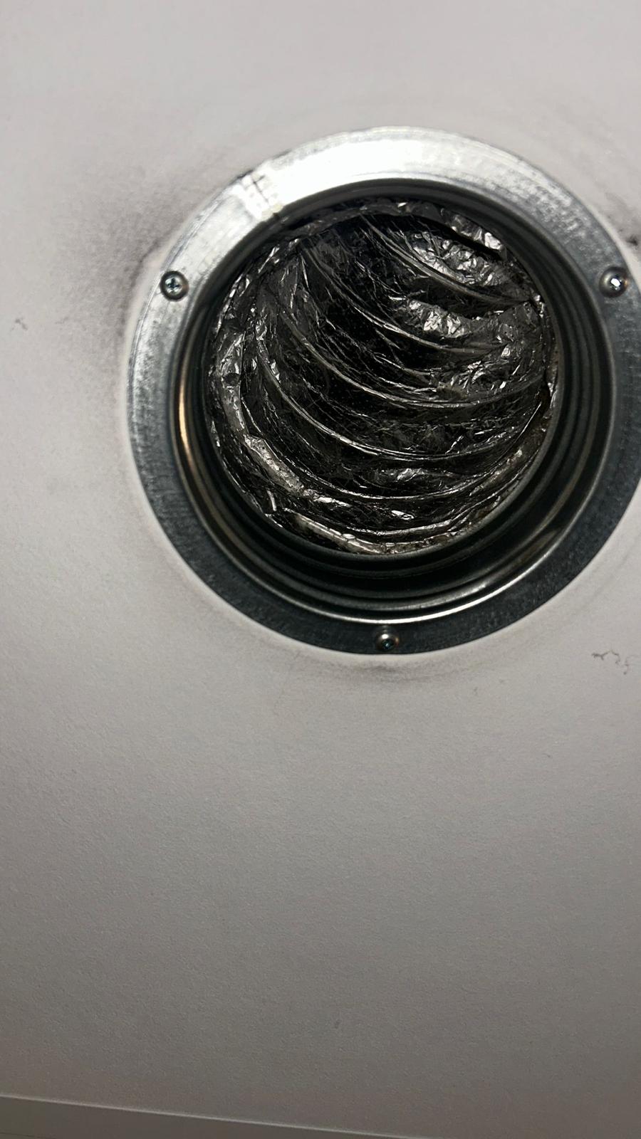Zicht in een ronde ventilatieopening met vervuilde buis