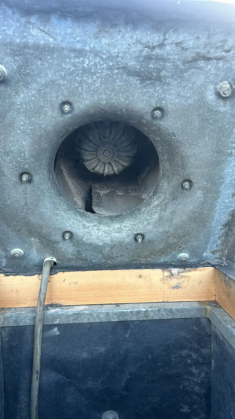 Axiale ventilator in een rond luchtkanaal, zichtbaar door een geopend kanaal.