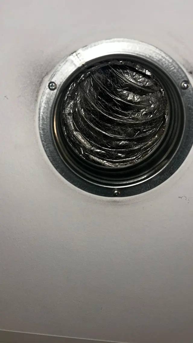 Ronde plafonddiffuser met een donkere, vettige laag op de luchtuitlaat.