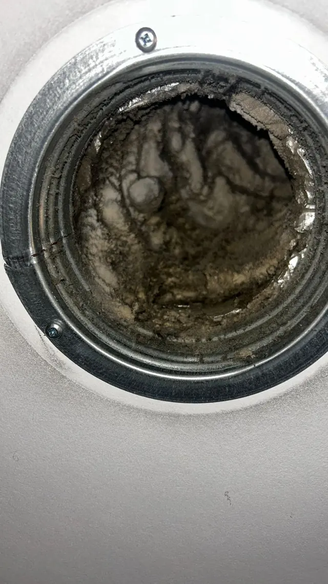 Ronde plafonddiffuser met een harde korst van stof en vet.