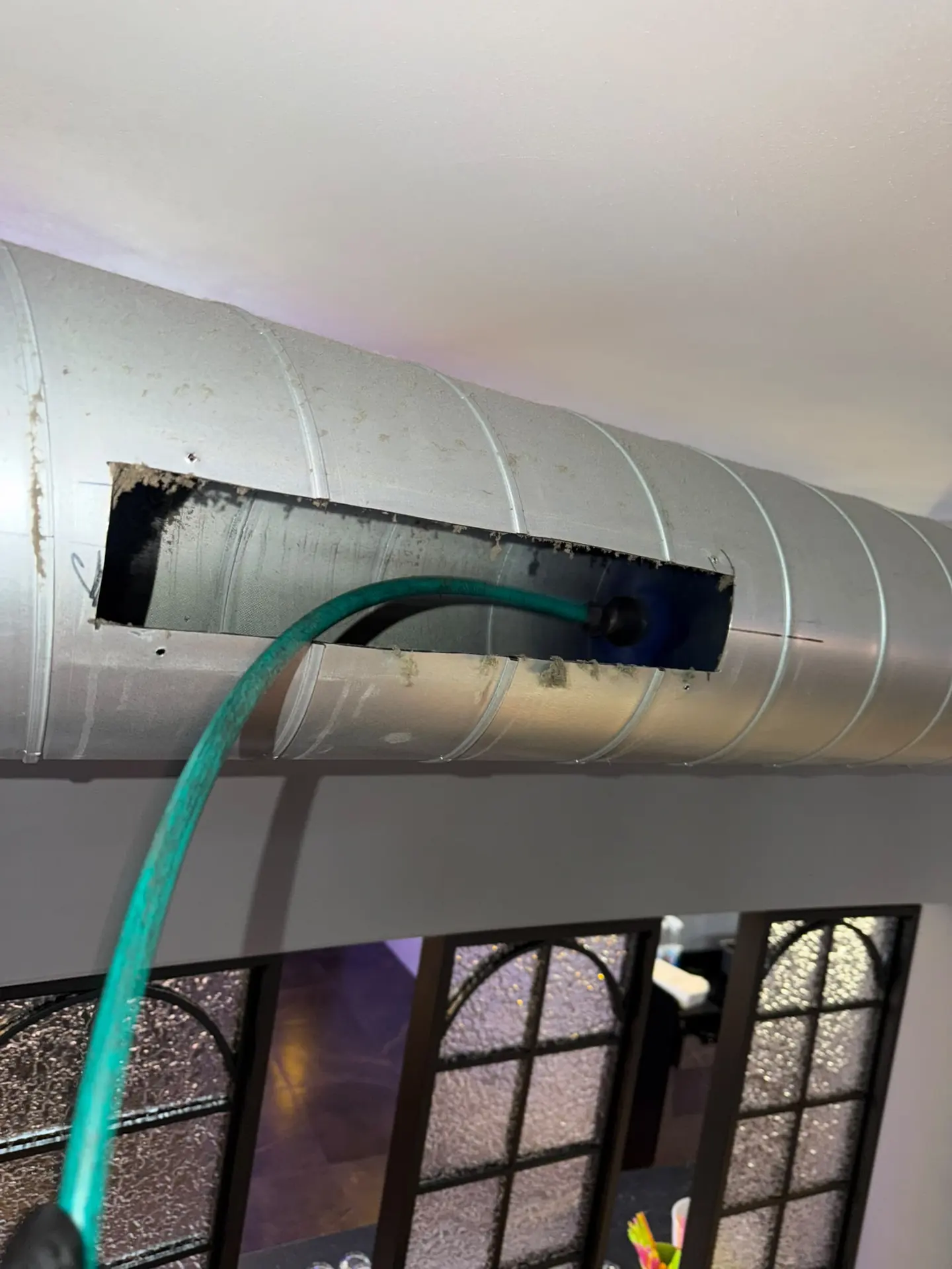 Rond spiraalkanaal in een gebouw met een geopende inspectieopening in de kanaalwand.